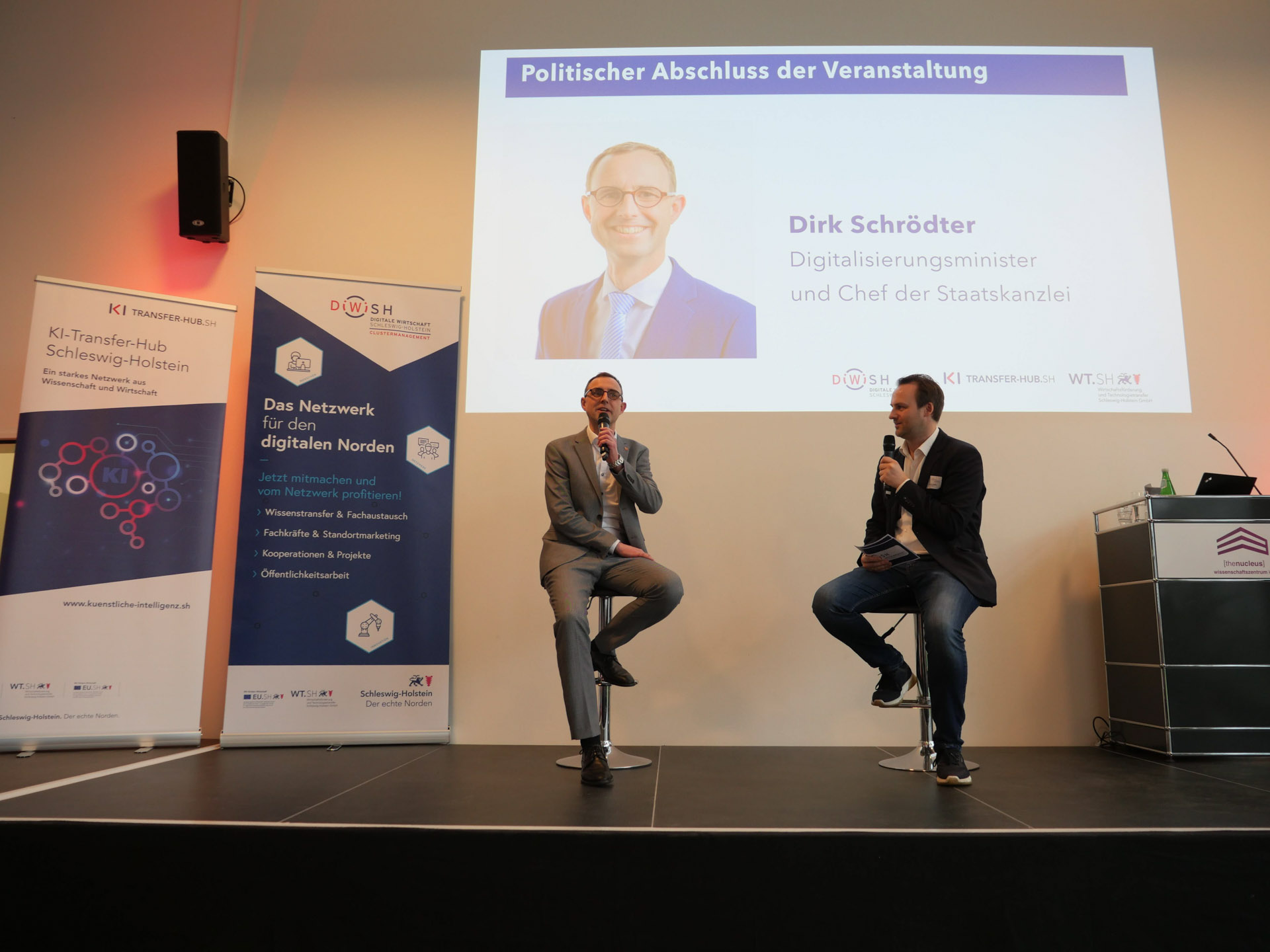 Dirk Schrödter und Johannis Ripken diskutieren auf einer Bühne